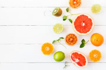 Schilderijen op glas Fruit background. Colorful fresh fruit on white table. Orange, tangerine, lime, kiwi, grapefruit. Flat lay, top view, copy space © Flaffy