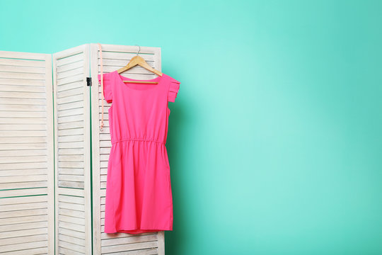 Pink dress hanging on folding screen on a green background