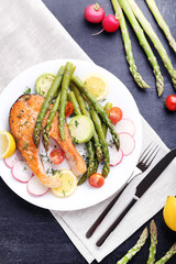 Steak of salmon with asparagus, vegetables, fork and knife