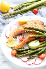 Steak of salmon with asparagus and vegetables on white plate