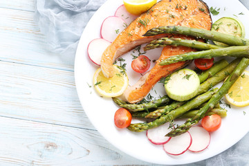 Steak of salmon with asparagus and vegetables on white plate