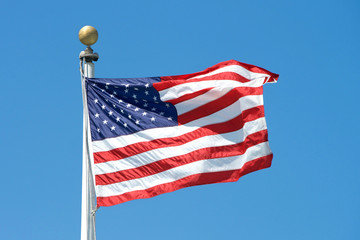 American flag waving in the wind with a clear blue sky background