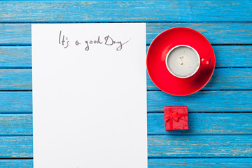 photo of paper It's a good day, cup of coffee and cute gift on the wonderful blue background