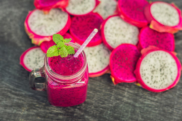 Smoothies of red organic dragon fruit and pieces of dragon fruit on an old wooden background