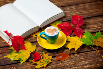 photo of cup of coffee, opened notebook and autumn leaves on the wonderful brown wooden background