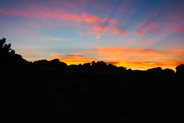Sun setting behind large stone spires in Canyonlands, Utah, creating a colofrul display on the clouds.  