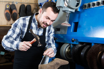 Fototapeta na wymiar male worker fixing failed shoes in shoe repair workshop