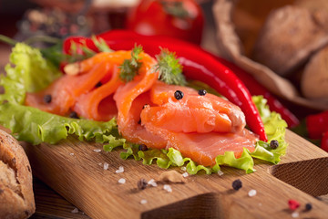 Slices of smoked salmon with dill, chile pepper, tomatoes and bread