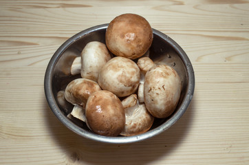 champignon mushrooms in bowl on wooden background