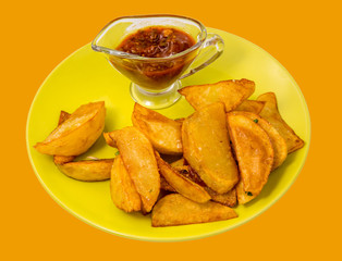 Fried potatoes with red sauce on a green plate isolated on white background