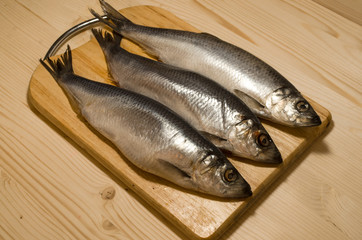 fresh fish herring on a chopping board on wooden table.