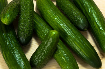 Green cucumbers on wooden table, top view