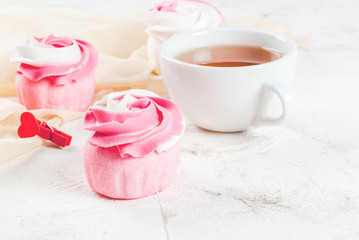 The concept of celebrating the mother's day. Spring relax. Cakes in the form of flowers (roses), with a cup of freshly brewed black tea, on a white stone table. Copy space