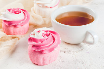 The concept of celebrating the mother's day. Spring relax. Cakes in the form of flowers (roses), with a cup of freshly brewed black tea, on a white stone table. Copy space