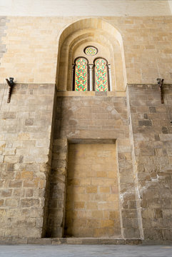Recessed arched frames and two colored stained glass windows in an old stone bricks wall, Medieval Cairo, Egypt