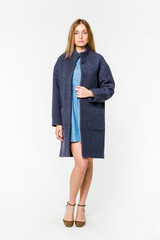 Beautiful young woman in coat posing on white background