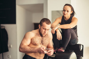 Athlete using mobile phone app fitness tracker for tracking weight loss progress during running exercise. Fit girl woman touching smartphone texting or playing online games or video workouts.