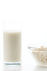 Milk in a glass, cottage cheese in a bowl, on a white table, in a high key, with space for text
