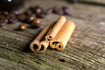 Cinnamon sticks with coffee grains on wooden background