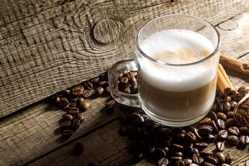 Cup of cappuccino and grain of coffee over wooden background
