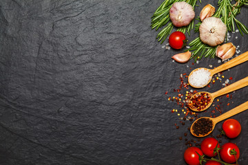 Colorful spices in spoons and tomatoes on dark vintage background. Top view. Food and cuisine ingredients.