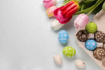 Painted easter eggs and bouquet of spring tulips closeup on a light blue background with space for congratulation