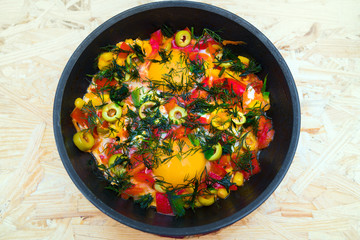 Eggs, olives, peppers, pan on table