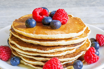 pile of homemade pancakes with fresh berries and honey