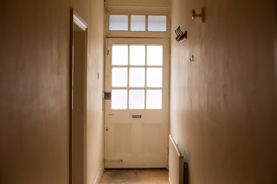 Old white wooden door with window from inside a corridor