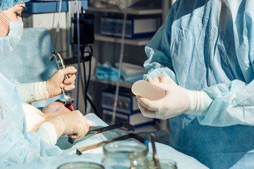 Surgeon wearing gloves operates women's breasts . Operation close up.