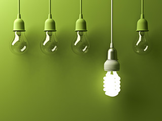 One hanging energy saving light bulb glowing different stand out from unlit incandescent lightbulbs with reflection on green background , leadership and different creative idea concept . 3D rendering.