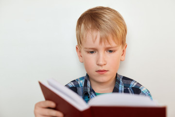 Education and school concept. A portrait of cute schoolboy with blond hair and attrractive blue eyes dressed in checked shirt holding a book preparing for the lessons isolated over white
