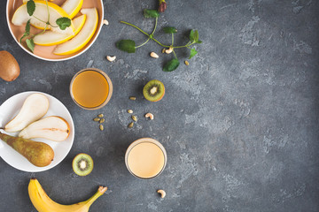 Fototapeta na wymiar Smoothie with pear, banana, melon, kiwi. Summer fruit cocktail on dark table. Vegan, vegetarian, detox, dieting concept. Flat lay, top view, copy space
