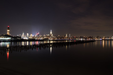 Fototapeta na wymiar Midtown and Downtown Manhattan Lit Skyline Reflecting in the Hudson at Night as Seen from Newport Green Park in Jersey City, USA