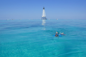 Swimmer at the reef with lighthouse in the background