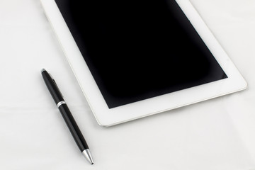Tablet computer and gold-blue pen on a white background, business concept.