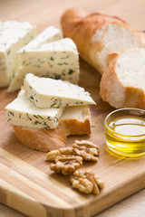 home made cheese and walnuts, olive oil and bread on a wooden board. brined curd white cheese with nuts on the table. Delicious food for breakfast or snack