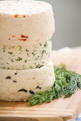 Variety of home made cheese  and herbs on a wooden board. brined curd white cheese on the table.