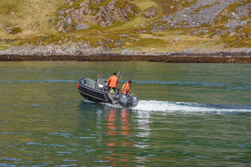 Fototapeta premium Two fishermen sail on a motor boat.