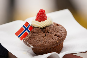 A chocolate cupcake  with Norwegian flag on a white napkin. Celebration ofr May 17th.
