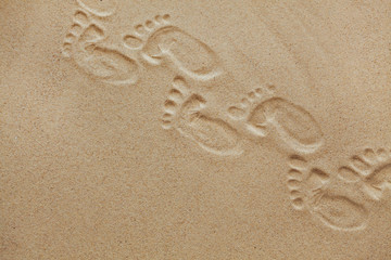 Fototapeta na wymiar Cute baby footsteps on sandy beach with space for text or desighn