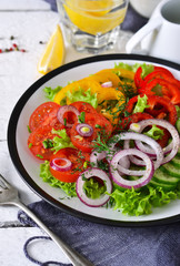 Vegetable mix salad with avocado and olive oil sauce on a white, wooden background.