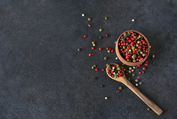 Black food background with spices. A mixture of peppers with a wooden spoon on a shale stone. Top...