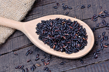 Black rice in a wooden spoon on table