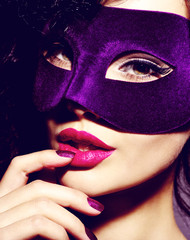 Beautiful  woman in violet theatre mask on face and purple nails