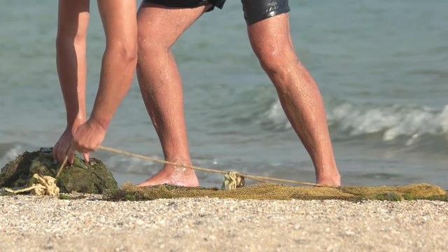 Fisherman with a seine on the beach. Man catches fish and shrimp in the sea. Net for fishing.