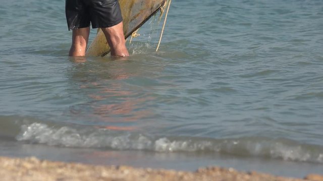 Man is washing the net in the sea. Fisherman catches a fish. Marine hobbies.