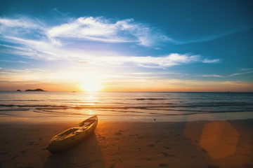 Naklejka na ściany i meble Sunset on the sea beach, a rowing boat on the shore.