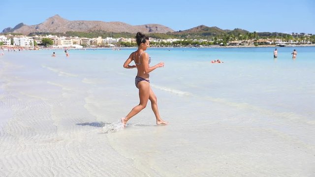 Slow motion, beautiful woman running and splashing water