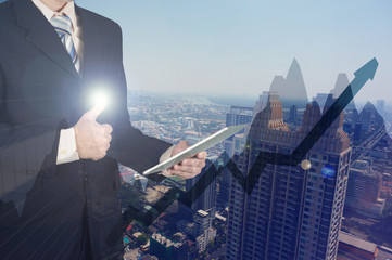 Double exposure of businessman using tablet and give thumbs up on financial graph chart and building background.